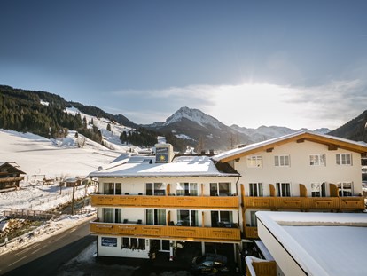 Hotels an der Piste - Dienten am Hochkönig - Außenansicht im Winter mit Piste im Hintergrund - Familienhotel Botenwirt ***S